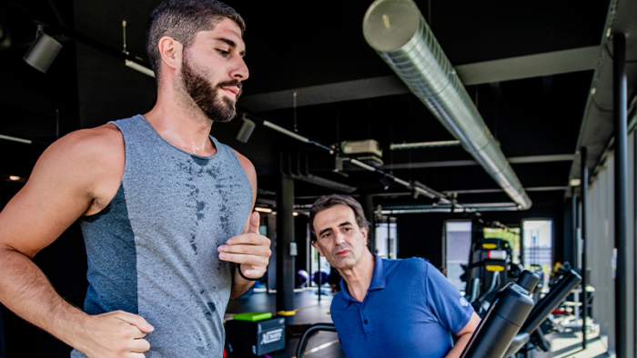 Sportlicher Mann rennt auf einem Laufband unter der Beobachtung eines Sport-Physiotherapeuten im Swiss Medical Network